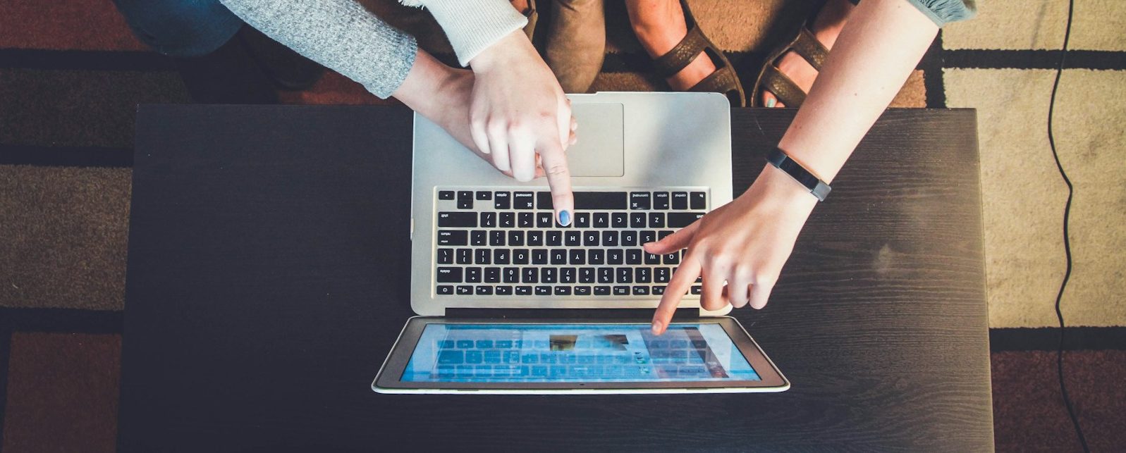 three person pointing the silver laptop computer