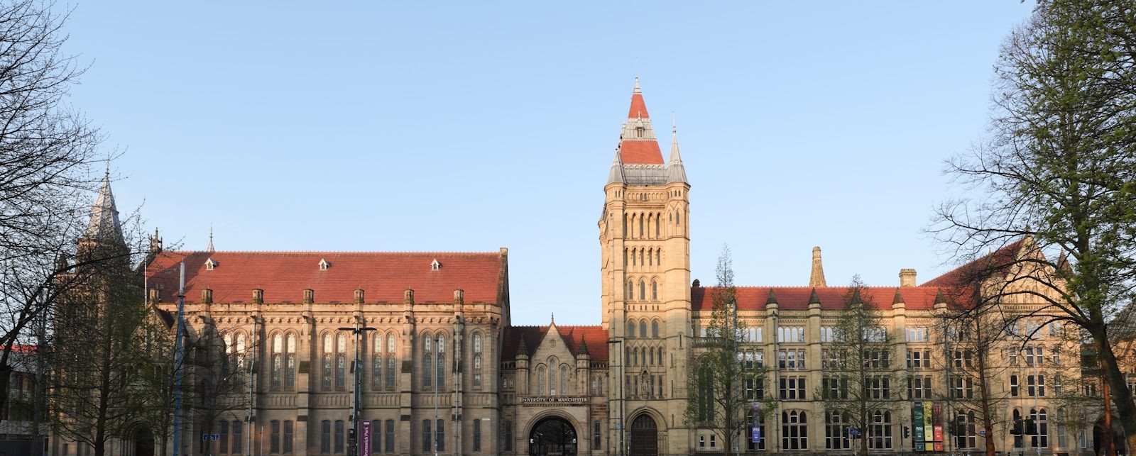 Large stone building with a tall tower and red roof.